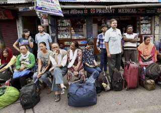 Stranded tourists wait at a bus stand in... Stranded tourists wait at a bus stand in...