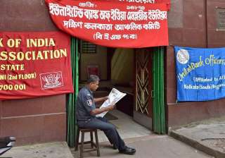 A security guard reads a newspaper in front of a... A security guard reads a newspaper in front of a...