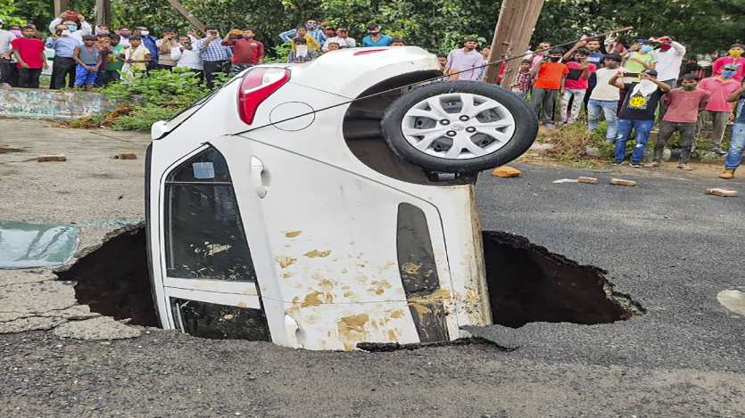 A car being pulled out as it got stuck after a road caved at Dwarka in New Delhi.