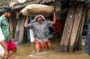 A person carries a grain sack as his house gets flooded