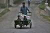 A Kashmiri farmer pushes a handcart with children on it on